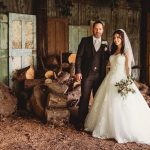 Bride and groom in rustic setting with wood logs.