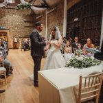 Bride and groom exchange rings at indoor wedding ceremony.