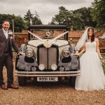 Bride and groom with vintage wedding car.