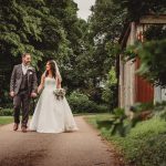 Bride and groom walking in lush garden.