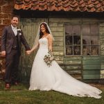 Bride and groom in front of rustic shed.