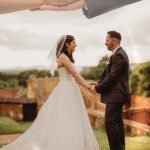 Bride and groom holding hands outdoors on wedding day.