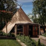 Large tipi tent in scenic countryside setting.