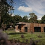 Wooden lodge surrounded by trees and greenery.