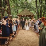 Wedding couple exits outdoor ceremony with confetti celebration.