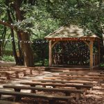 Woodland ceremony area with wooden seating and gazebo.