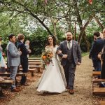 Bride and groom walk down outdoor aisle