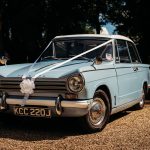 Classic wedding car with decorative white ribbon.