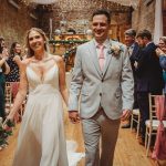 Bride and groom walking down the aisle, smiling.