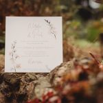 Wedding invitation with floral design outdoors.