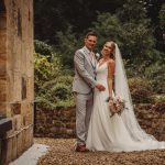 Bride and groom pose in garden.