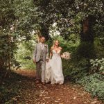 Bride and groom walking through forest path