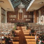 Sunlit wedding venue with floral decorations and chairs.