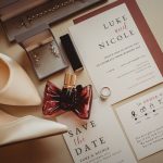 Wedding invitation, jewellery, perfume, and shoes arranged neatly.