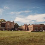 Historic red brick country house in sunny garden.