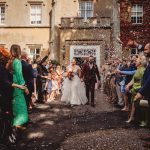 Bride and groom walk through confetti at wedding.