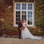 Wedding couple in front of ivy-covered building.