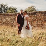 Couple in wedding attire by rustic brick wall