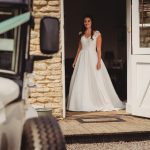 Bride in white dress standing in doorway.