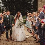 Bride and groom walk through confetti-throwing guests.