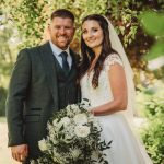 Smiling couple on wedding day under trees.