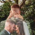 Bride and groom embrace in garden setting.