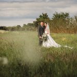 Bride and groom standing in a lush field