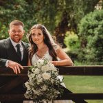 Smiling couple on wedding day by garden gate