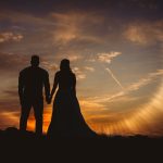 Silhouetted couple holding hands at sunset.