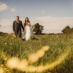 Bride and groom walking in sunny field