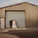 Couple posing outside rustic wooden building.