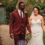 Bride and groom walking in garden, holding hands.