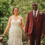 Happy couple in wedding attire holding hands outdoors.