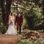 Bride and groom walk through wooded pathway