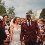 Wedding couple smiling, surrounded by guests and confetti.