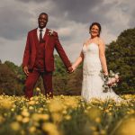 Smiling couple in field on wedding day.