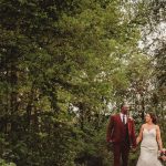 Couple walking in forest, wedding attire, summer day.