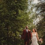 Bride and groom walking in forest.