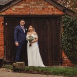 Couple posing in front of rustic wooden door.