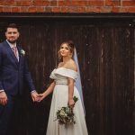 Couple holding hands at rustic wedding.