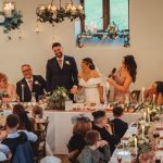 Wedding speeches at a decorated banquet table.