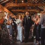 Bride and groom walking through applauding guests