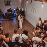 Bride and groom dancing at wedding reception with guests.