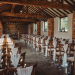 Rustic wedding venue with wooden chairs and decorations.