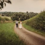 Bride and groom walking on country path