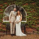 Couple posing in front of ivy-covered wall