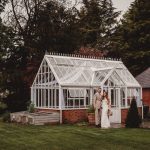 Bride and groom outside charming glasshouse.