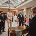 Wedding ceremony with bride, groom, and officiant indoors.