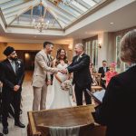 Groom shakes hands with father during wedding ceremony.