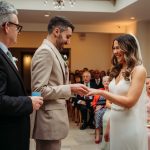 Bride and groom exchanging wedding rings indoors.